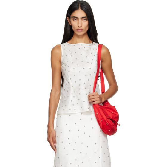 A woman wearing a white dotted RESCHA tank top and matching skirt with a red shoulder bag