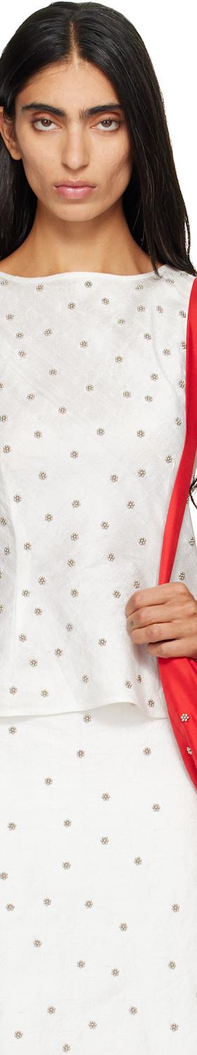 A woman wearing a white dotted RESCHA tank top and matching skirt with a red shoulder bag