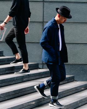 Two men walking down city steps in navy workwear and dark leather sneakers