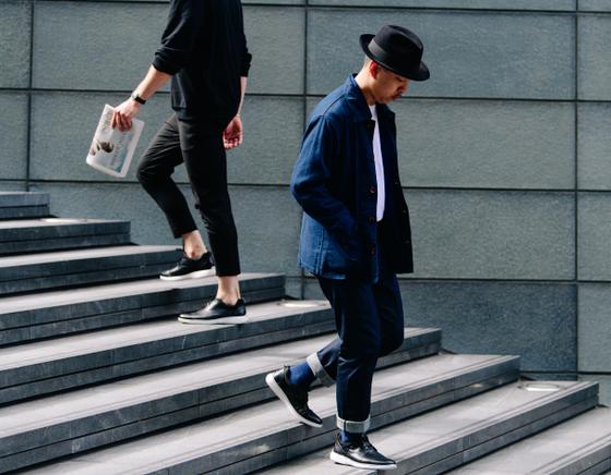 Two men walking down city steps in navy workwear and dark leather sneakers