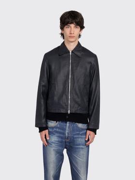 A man wearing a black coated denim zip jacket with faded blue jeans