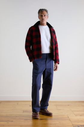 A man wearing a red and black buffalo check Rosa Rugosa jacket with navy work pants