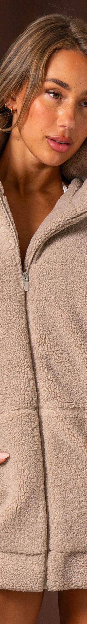 A woman wearing an oversized taupe Ryderwear sherpa zip jacket