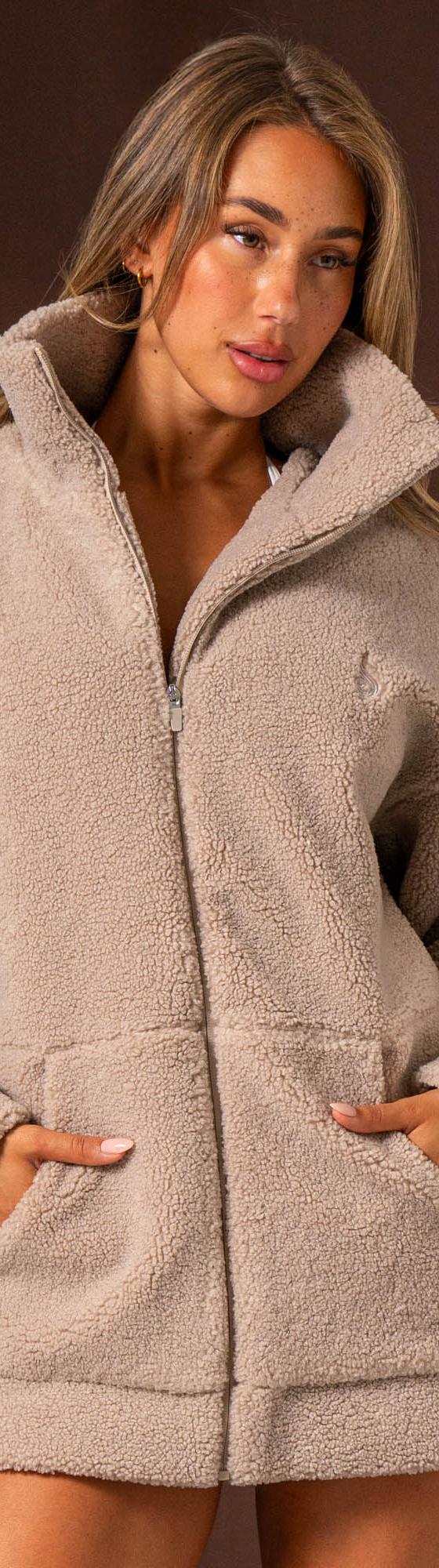 A woman wearing an oversized taupe Ryderwear sherpa zip jacket