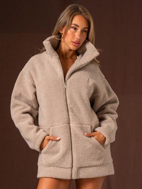 A woman wearing an oversized taupe Ryderwear sherpa zip jacket