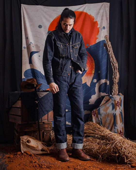 A man wearing a Samurai Jeans indigo denim jacket and matching selvedge jeans with brown leather boots