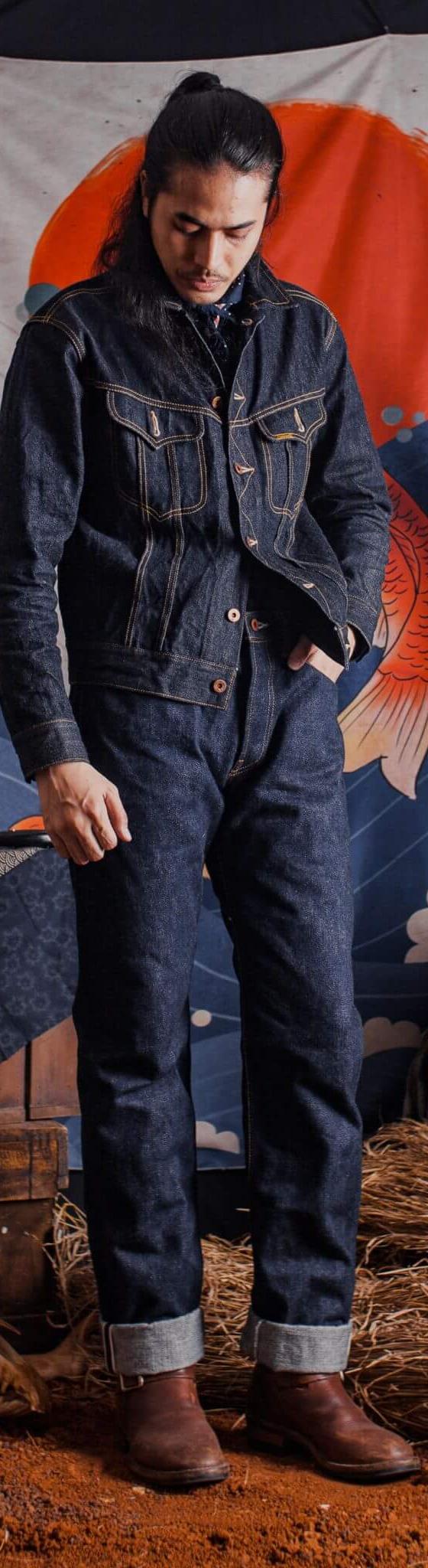 A man wearing a Samurai Jeans indigo denim jacket and matching selvedge jeans with brown leather boots