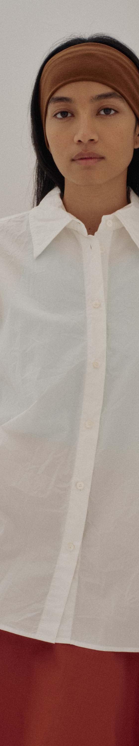 A woman wearing a white SAYAKA DAVIS cotton shirt with a rust-toned skirt