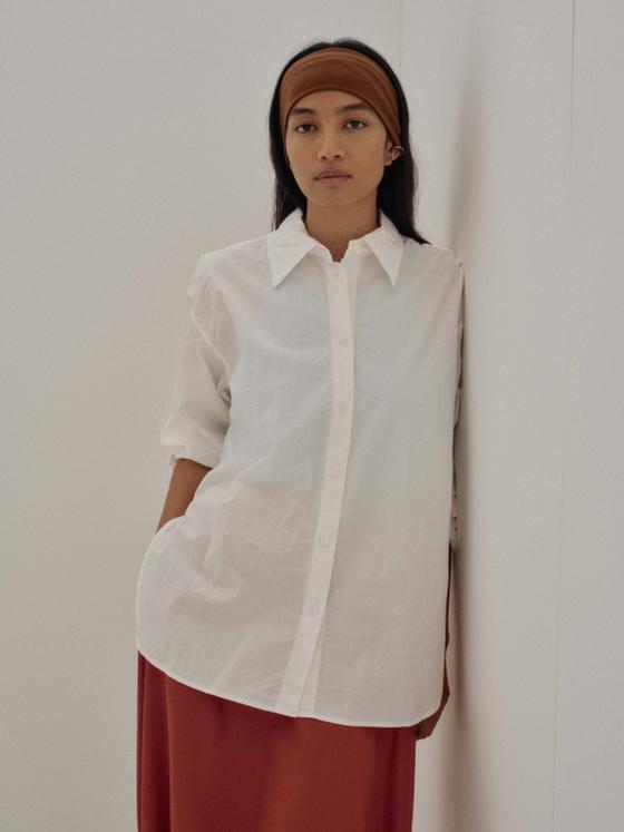 A woman wearing a white SAYAKA DAVIS cotton shirt with a rust-toned skirt