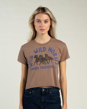 A woman wearing a brown Sendero Provisions Co. Wild Horses cropped tee with dark denim jeans