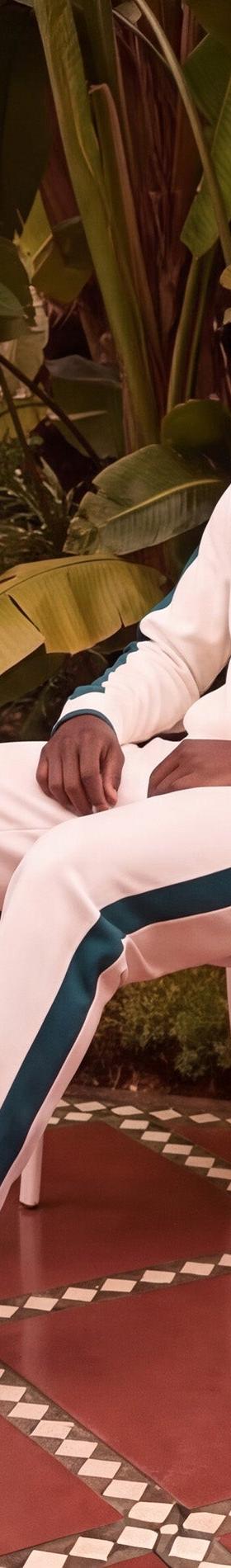 Sergio Tacchini model seated in a cream and green track suit