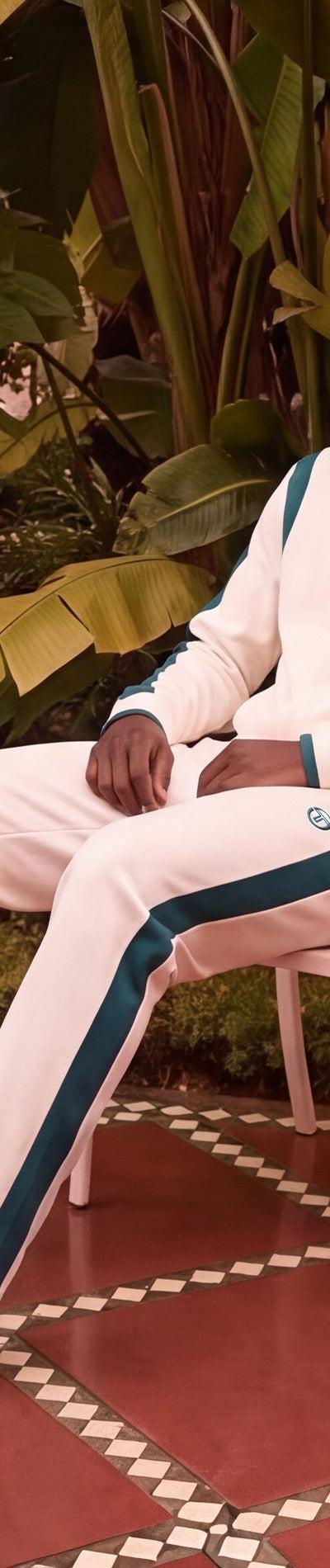 Sergio Tacchini model seated in a cream and green track suit