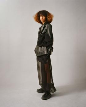 A woman wearing a black Setchu leather jacket over a sheer black organza skirt