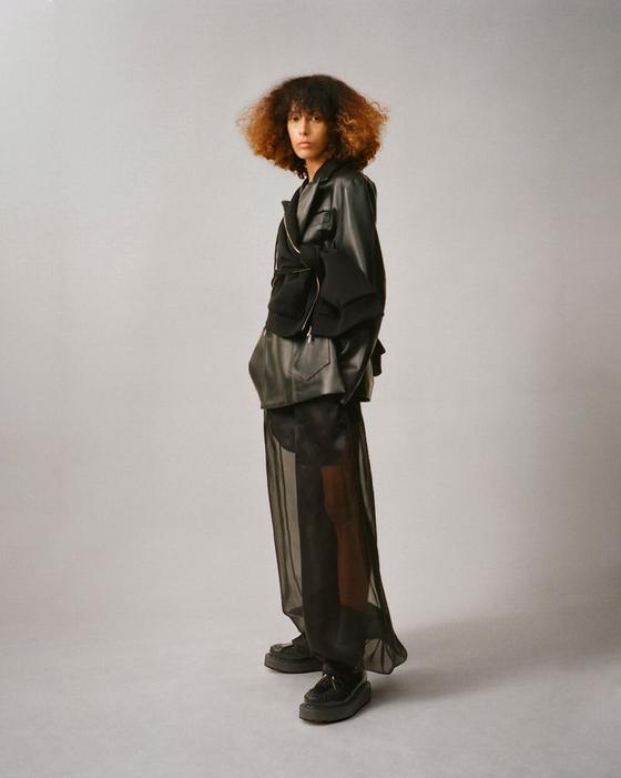 A woman wearing a black Setchu leather jacket over a sheer black organza skirt