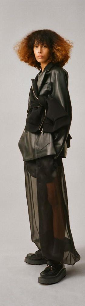 A woman wearing a black Setchu leather jacket over a sheer black organza skirt