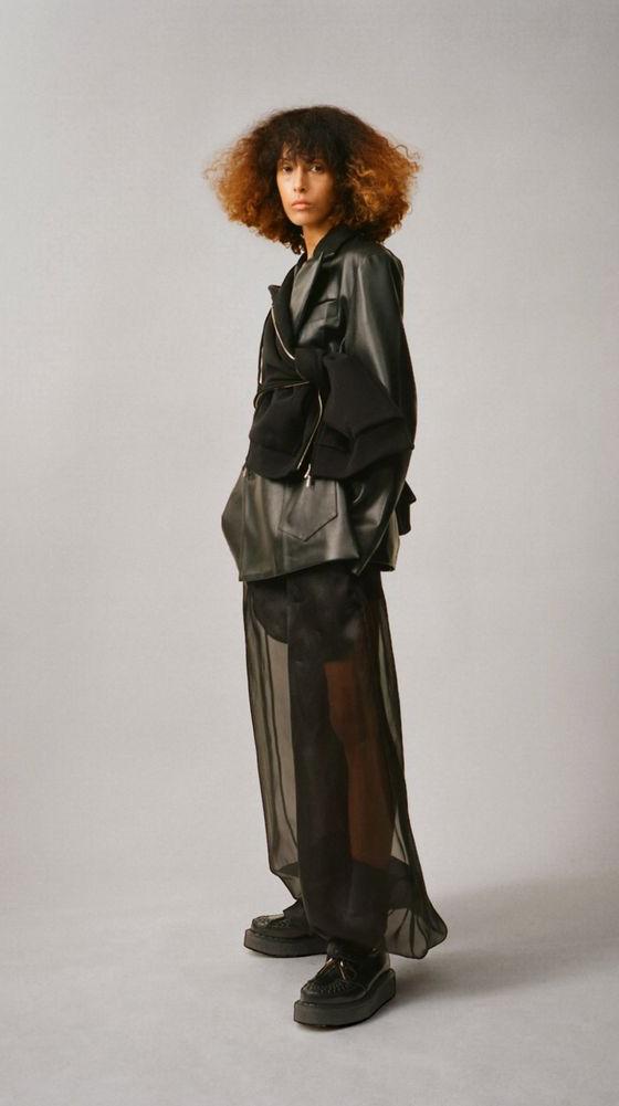 A woman wearing a black Setchu leather jacket over a sheer black organza skirt