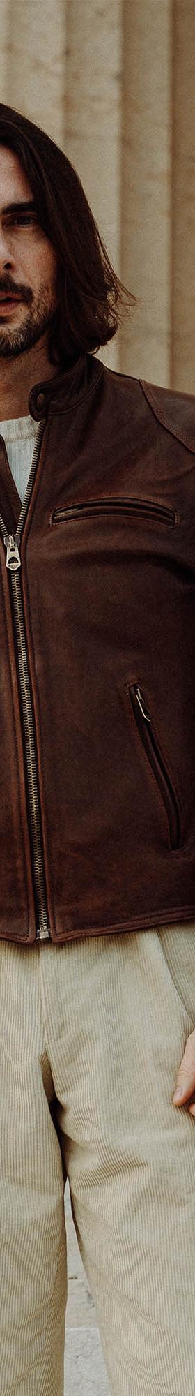 A man wearing a brown Shangri-La Heritage horsehide café racer jacket with cream trousers