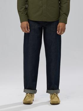 A man wearing raw selvedge Shockoe Atelier jeans with cuffed hems and an olive overshirt