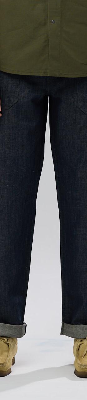 A man wearing raw selvedge Shockoe Atelier jeans with cuffed hems and an olive overshirt