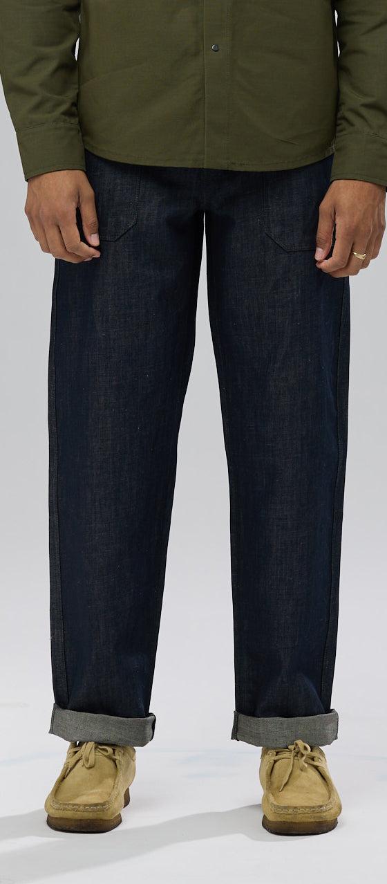 A man wearing raw selvedge Shockoe Atelier jeans with cuffed hems and an olive overshirt