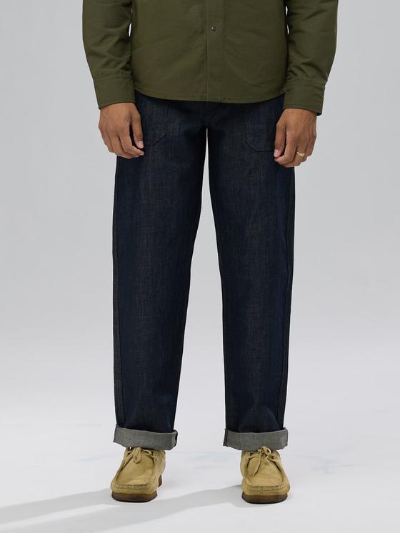 A man wearing raw selvedge Shockoe Atelier jeans with cuffed hems and an olive overshirt