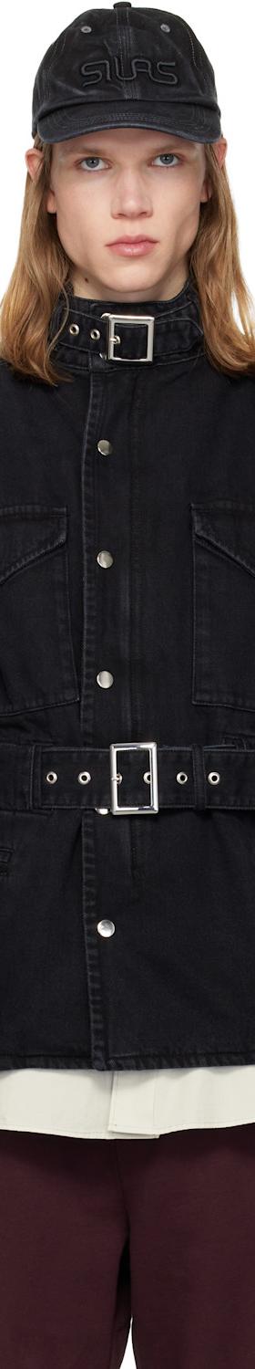 A man wearing a black belted denim jacket and cap by Silas