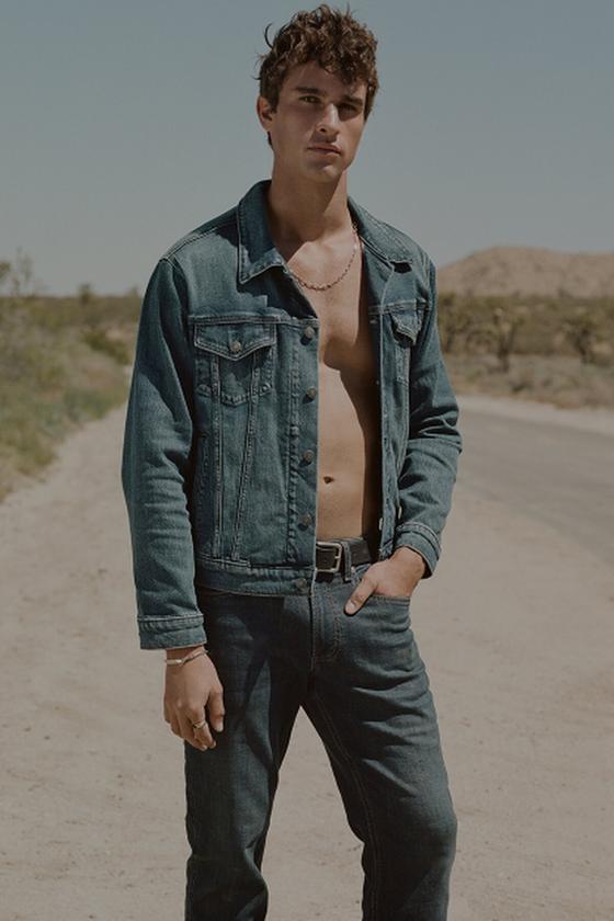 A man wearing a Silver Jeans Co. denim trucker jacket and jeans on a desert road