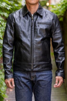 A man wearing a black Simmons Bilt leather jacket with raw denim jeans