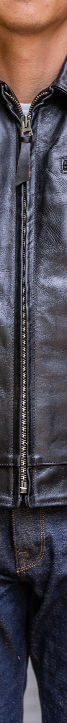 A man wearing a black Simmons Bilt leather jacket with raw denim jeans