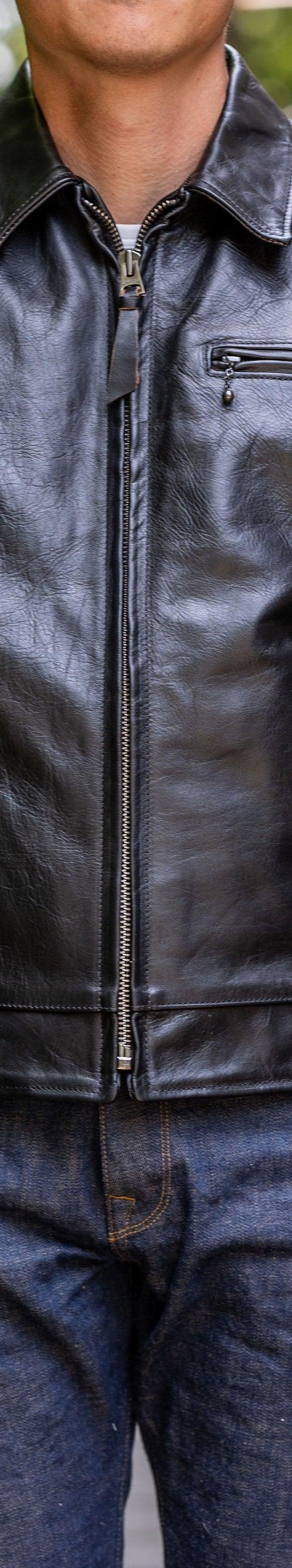 A man wearing a black Simmons Bilt leather jacket with raw denim jeans