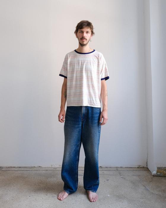 A man wearing a striped ringer t-shirt and faded wide-leg jeans by Small Talk Studio