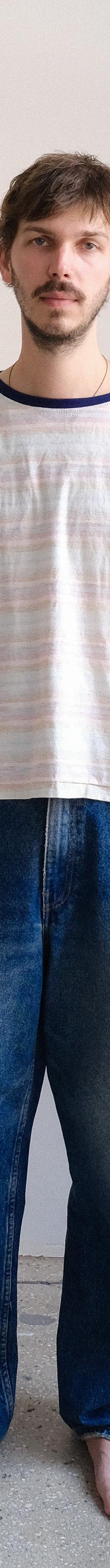 A man wearing a striped ringer t-shirt and faded wide-leg jeans by Small Talk Studio
