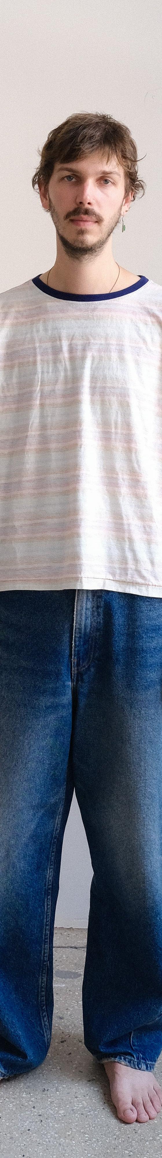 A man wearing a striped ringer t-shirt and faded wide-leg jeans by Small Talk Studio