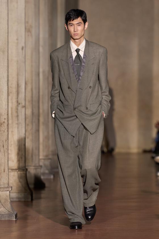 A man wearing a grey oversized double-breasted Soshiotsuki suit with wide pleated trousers