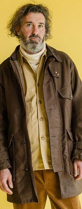 A man wearing a brown Soundman field jacket over a mustard shirt and corduroy trousers