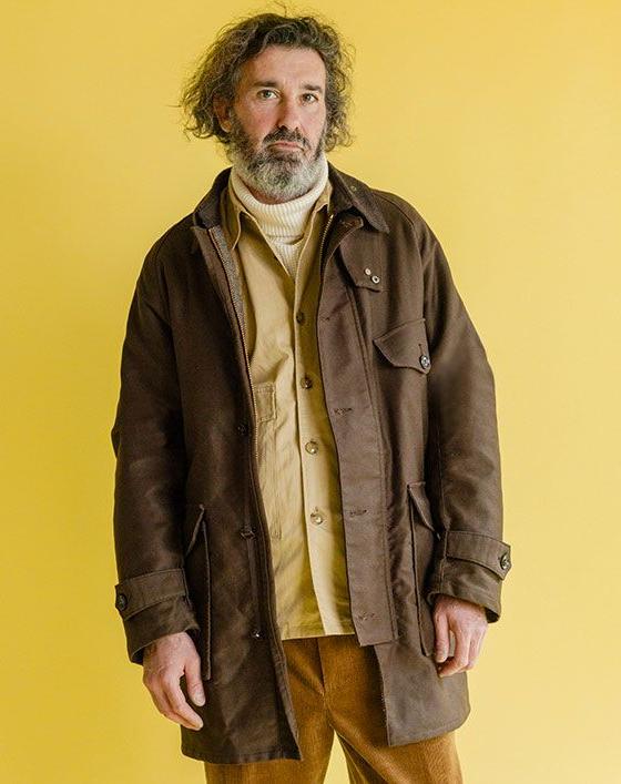 A man wearing a brown Soundman field jacket over a mustard shirt and corduroy trousers