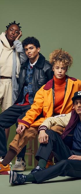 Four models in Stadium Goods varsity jackets, hoodies and sneakers against a green backdrop