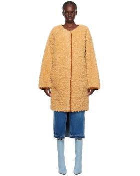 A woman wearing a beige faux fur Stand Studio coat with jeans and blue boots