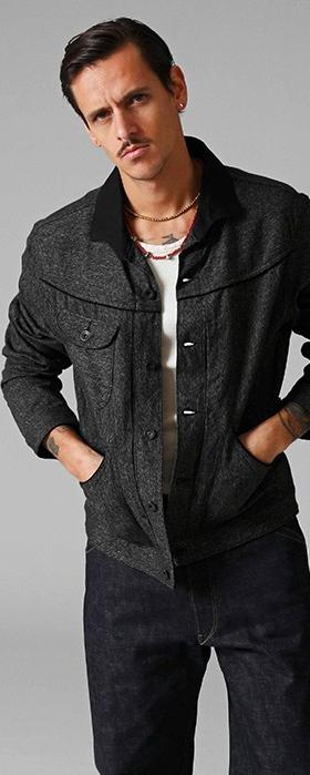 A man wearing a dark tweed Stevenson Overall Co. Western jacket with indigo selvedge denim jeans