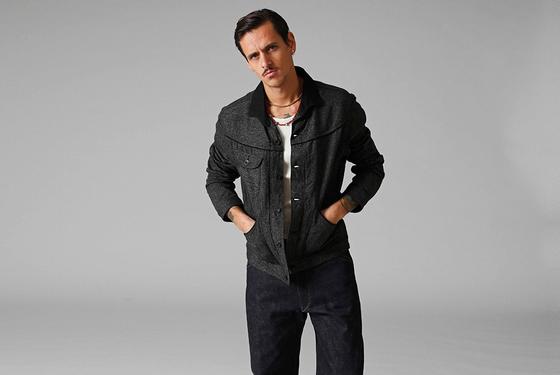 A man wearing a dark tweed Stevenson Overall Co. Western jacket with indigo selvedge denim jeans