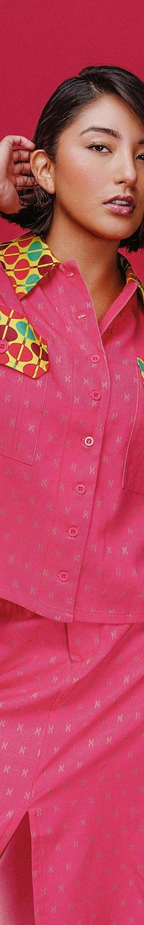 A woman wearing a pink patch-pocket camp shirt and matching midi skirt