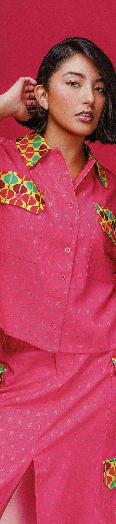 A woman wearing a pink patch-pocket camp shirt and matching midi skirt
