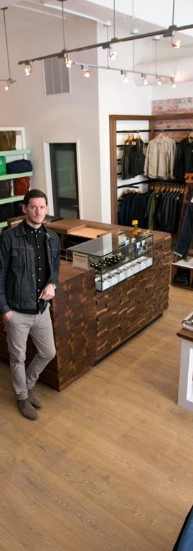 A man in a dark denim jacket standing in a menswear boutique lined with denim, knitwear and shirting