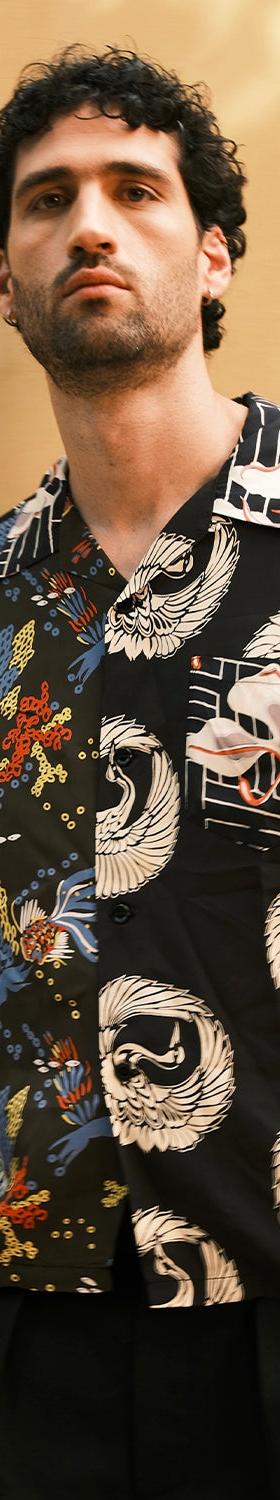 A man wearing a black Sun Surf rayon aloha shirt with Japanese crane and fan motifs