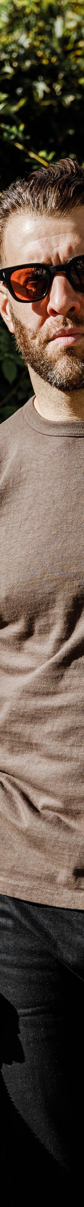 A man wearing a brown Sunray Sportswear t-shirt with black jeans