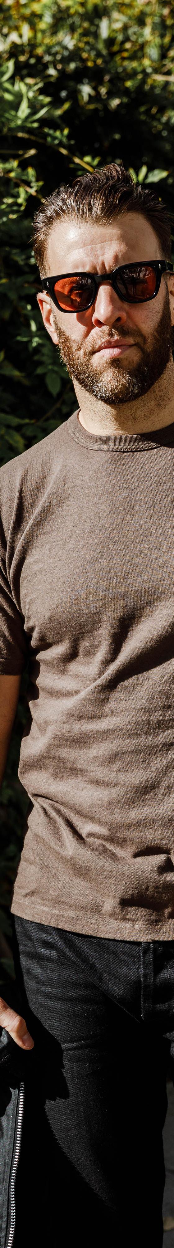 A man wearing a brown Sunray Sportswear t-shirt with black jeans