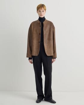 A woman wearing a brown suede Taiga Takahashi jacket with a black turtleneck and black trousers