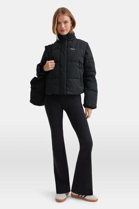 A woman wearing a black TALA puffer jacket with black flared leggings