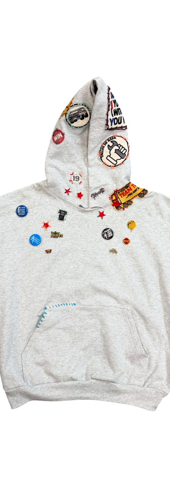 A grey Taller de Rafa hoodie covered in enamel pins and patches on a plain white background