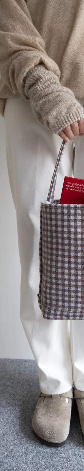A woman holding a checked cotton canvas Tembea tote bag